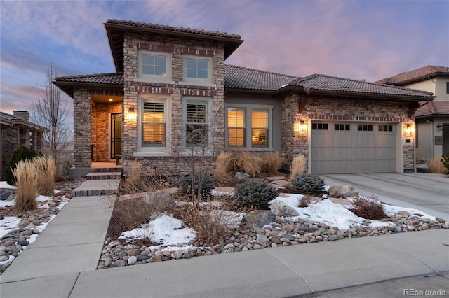 view of front facade featuring concrete driveway, an attached garage, a tile roof, and stucco siding