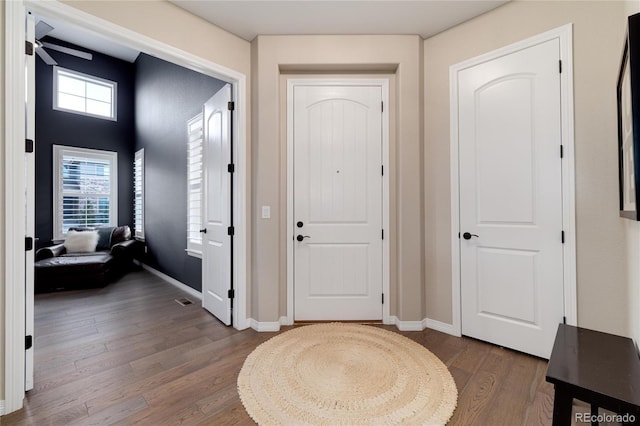 foyer with dark wood-style floors and baseboards