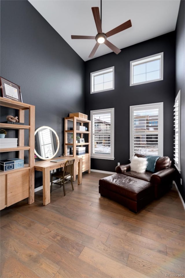 bedroom with wood finished floors, a towering ceiling, and baseboards