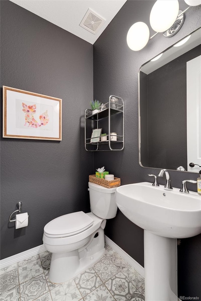 bathroom with toilet, baseboards, visible vents, and a sink