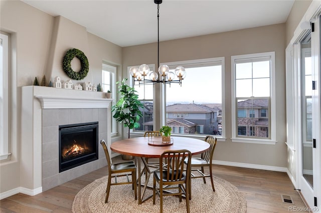 dining space with a healthy amount of sunlight, a tiled fireplace, and wood finished floors