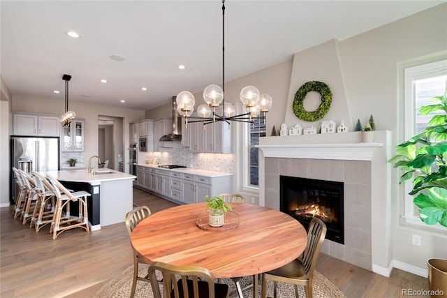 dining area with recessed lighting, baseboards, wood finished floors, and a tile fireplace