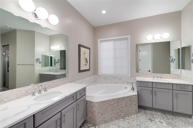 full bathroom with a garden tub, two vanities, and a sink