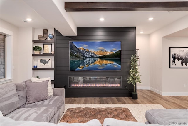 interior space featuring beamed ceiling, a fireplace, wood finished floors, and baseboards