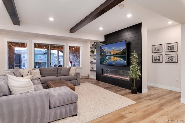 living area featuring beamed ceiling, a fireplace, wood finished floors, and baseboards