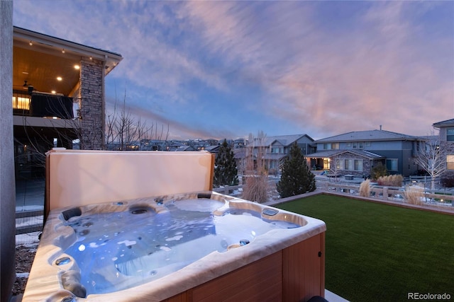 yard at dusk featuring a residential view and a hot tub