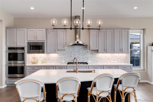 kitchen featuring wall chimney range hood, appliances with stainless steel finishes, light countertops, and backsplash