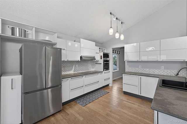 7330 Cotton Dr, Colorado Springs, CO 80923 - kitchen featuring appliances with stainless steel finishes, dark countertops, a sink, vaulted ceiling, and decorative backsplash
