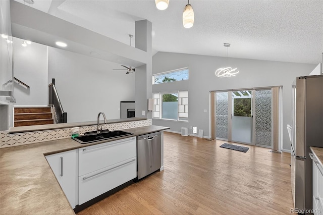 7330 Cotton Dr, Colorado Springs, CO 80923 - kitchen featuring appliances with stainless steel finishes, a sink, high vaulted ceiling, light wood-type flooring, and white cabinets