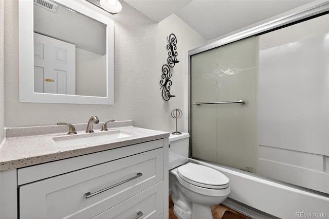 7330 Cotton Dr, Colorado Springs, CO 80923 - bathroom featuring vanity, enclosed tub / shower combo, toilet, a textured wall, and wood finished floors