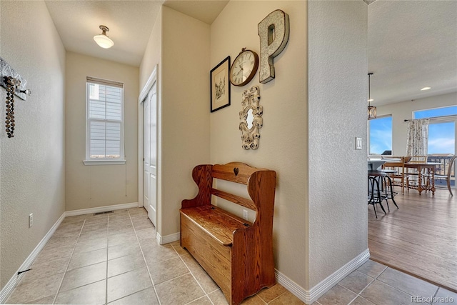 interior space featuring visible vents, baseboards, light tile patterned flooring, and a textured wall