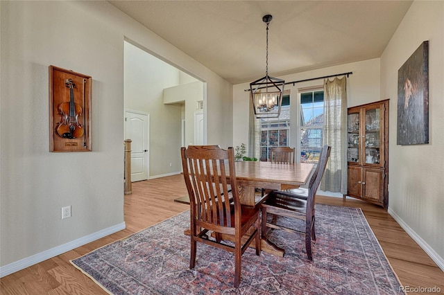 dining area with an inviting chandelier, light wood-style flooring, and baseboards