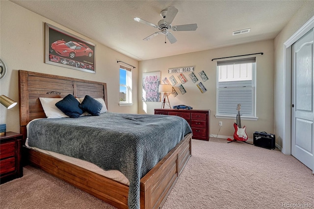 bedroom with visible vents, multiple windows, a textured ceiling, and carpet