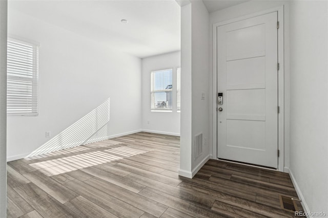 foyer entrance featuring visible vents, baseboards, and wood finished floors