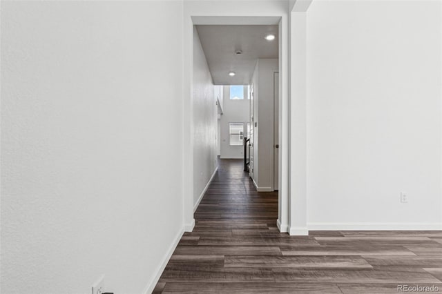 corridor featuring baseboards and dark wood-style flooring