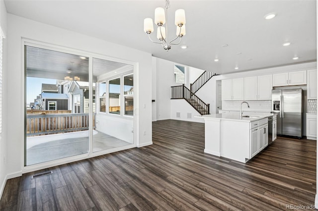 kitchen with a sink, backsplash, light countertops, stainless steel appliances, and dark wood-style flooring