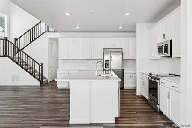 kitchen featuring visible vents, light countertops, dark wood-style floors, stainless steel appliances, and a kitchen island with sink