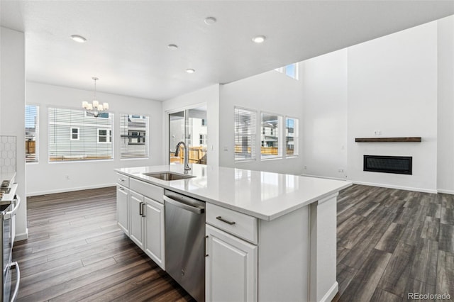 kitchen featuring a sink, stainless steel dishwasher, dark wood-style floors, a glass covered fireplace, and a chandelier