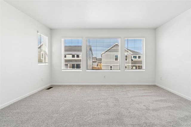 unfurnished room featuring carpet flooring, visible vents, and baseboards