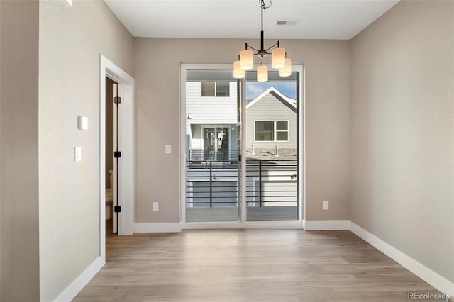 unfurnished dining area featuring a notable chandelier and light wood-type flooring