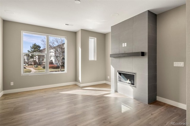 unfurnished living room with a fireplace and light wood-type flooring