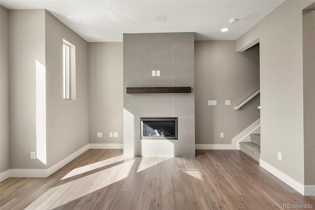 unfurnished living room featuring a tile fireplace and light wood-type flooring