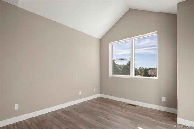 spare room with vaulted ceiling and light hardwood / wood-style floors