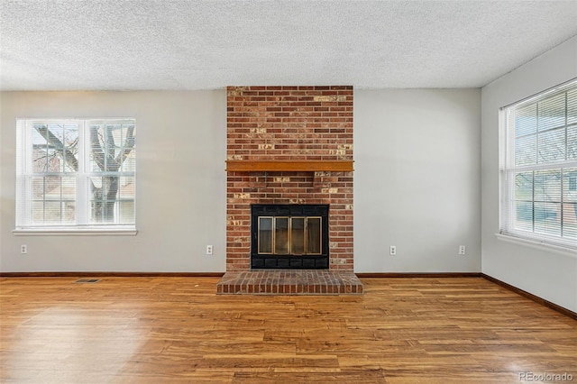 unfurnished living room featuring a fireplace, baseboards, and wood finished floors