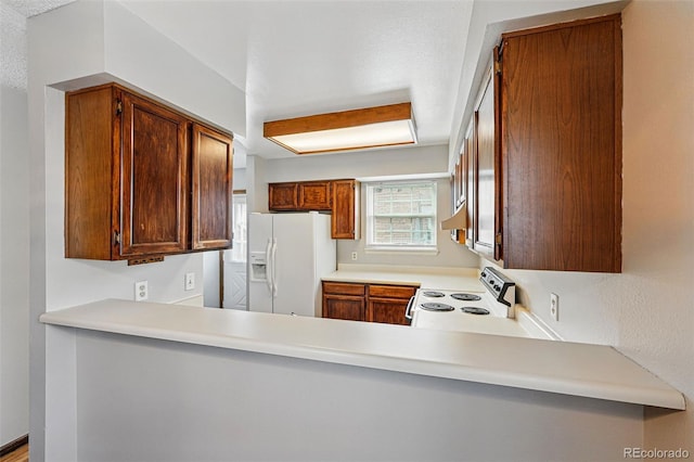 kitchen with under cabinet range hood, white appliances, and light countertops