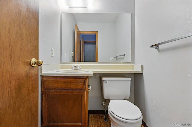 bathroom with toilet, wood finished floors, and vanity