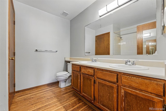 full bathroom with a sink, visible vents, toilet, and wood finished floors