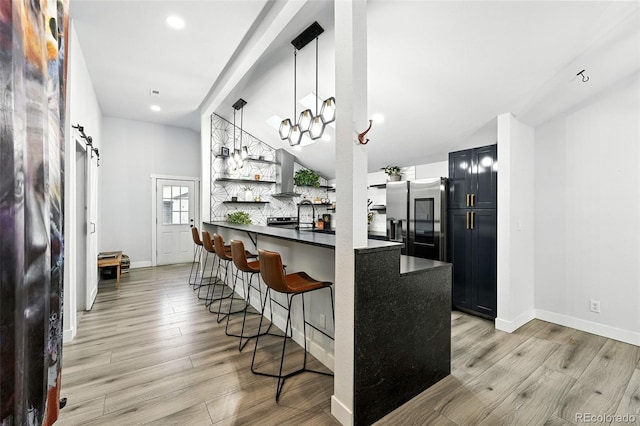2500 Estes St, Lakewood, CO 80215 - kitchen with stainless steel fridge, a kitchen bar, dark countertops, open shelves, and light wood-type flooring