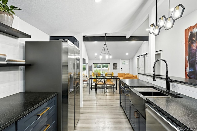 2500 Estes St, Lakewood, CO 80215 - kitchen with a barn door, appliances with stainless steel finishes, light wood finished floors, open shelves, and decorative light fixtures