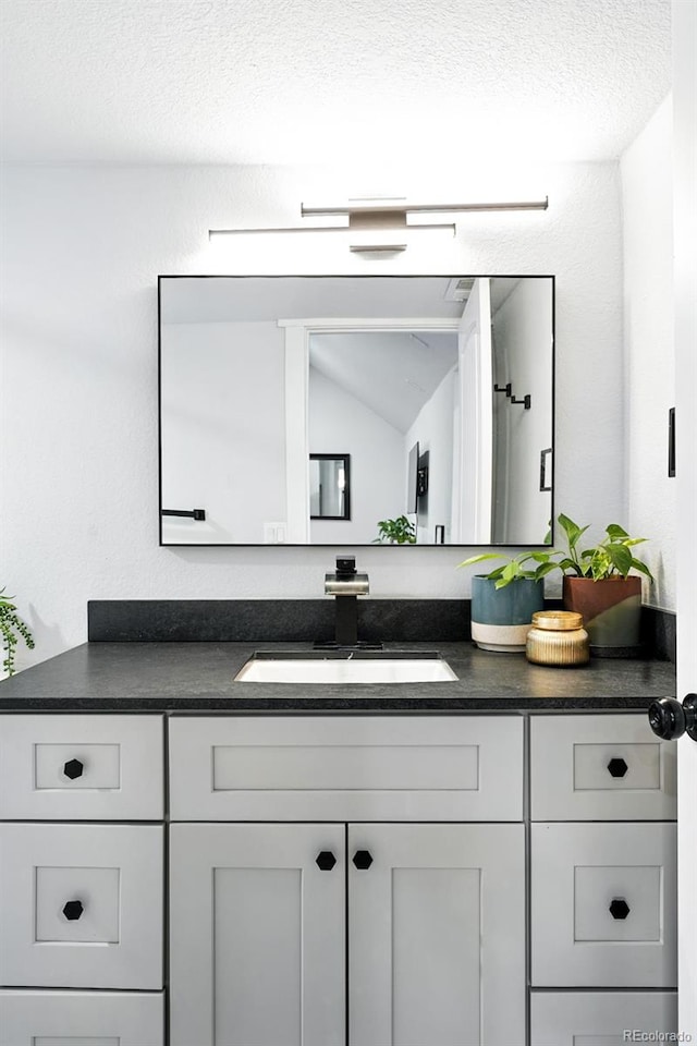2500 Estes St, Lakewood, CO 80215 - bathroom with vanity, lofted ceiling, and a textured ceiling