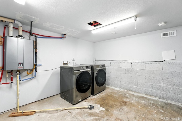 2500 Estes St, Lakewood, CO 80215 - laundry room featuring washing machine and clothes dryer, water heater, a textured ceiling, and concrete block wall