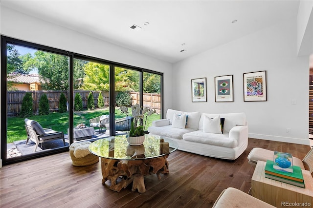 living area featuring visible vents, baseboards, vaulted ceiling, and wood finished floors