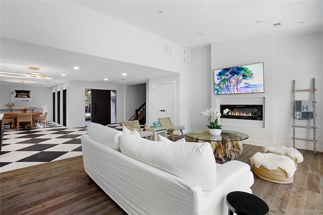 living room with visible vents, dark wood finished floors, a glass covered fireplace, stairway, and recessed lighting