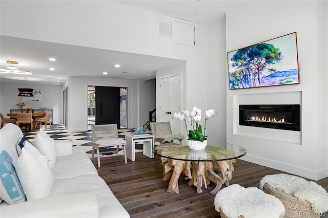 living room with recessed lighting, a high ceiling, baseboards, dark wood-style floors, and a glass covered fireplace