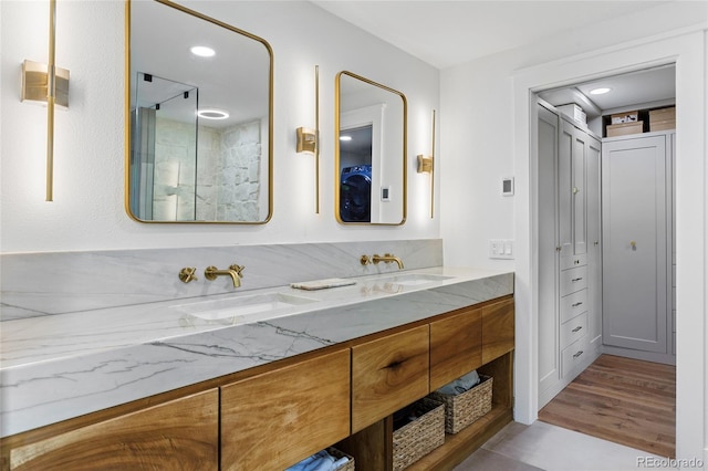 full bath featuring a closet, wood finished floors, a sink, and double vanity