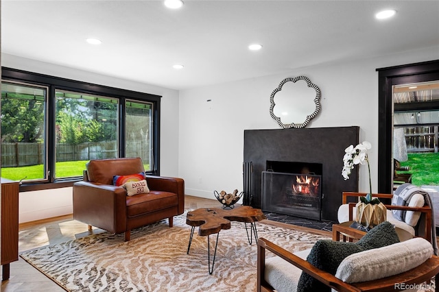 living room featuring a fireplace with flush hearth, recessed lighting, baseboards, and wood finished floors