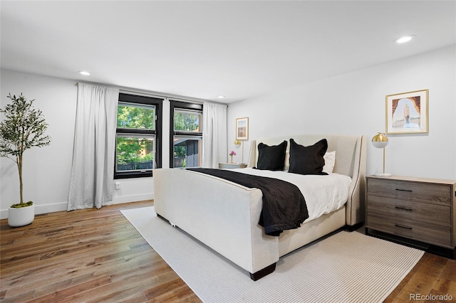 bedroom featuring baseboards, wood finished floors, and recessed lighting