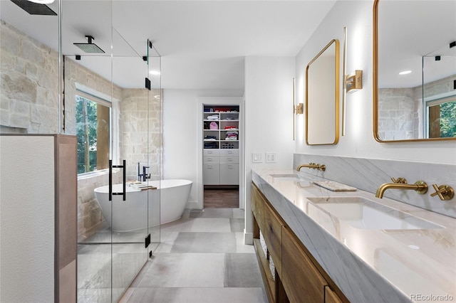 bathroom with a freestanding tub, tiled shower, a sink, and double vanity