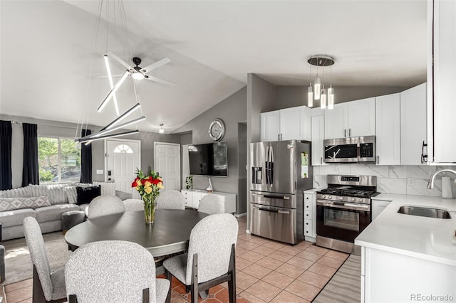 3296 S Bryant St, Englewood, CO 80110 - kitchen featuring stainless steel appliances, a sink, open floor plan, vaulted ceiling, and light countertops