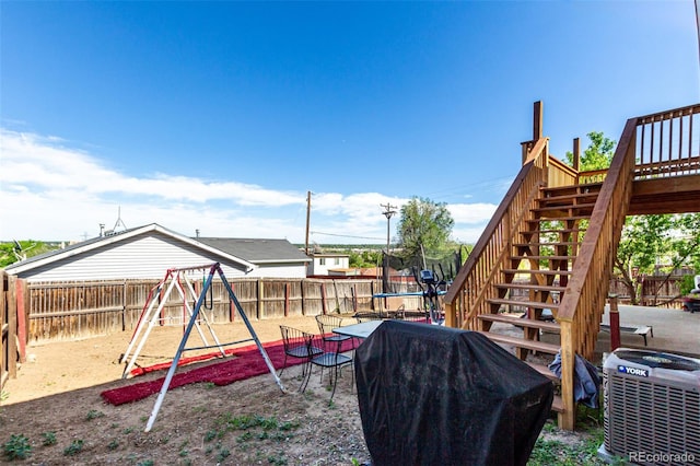 3296 S Bryant St, Englewood, CO 80110 - view of playground featuring a trampoline, stairway, central air condition unit, a fenced backyard, and a deck