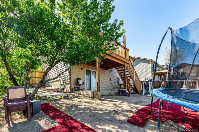 3296 S Bryant St, Englewood, CO 80110 - rear view of house with a trampoline, stairway, a deck, and fence
