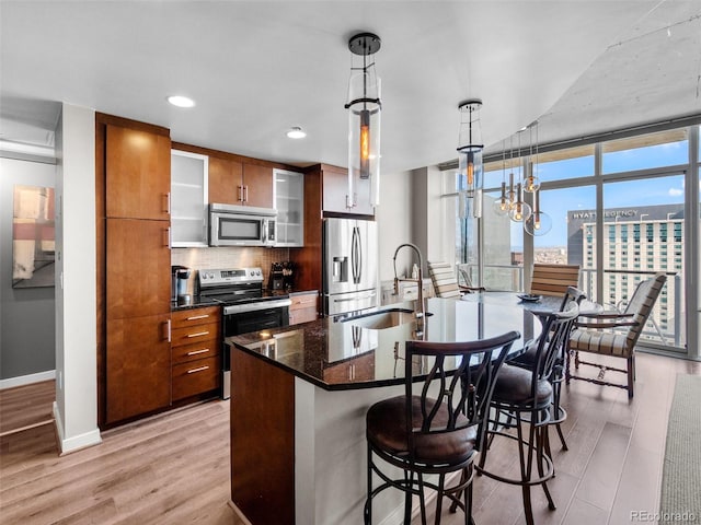 891 14th St Unit 3410, Denver, CO 80202 - kitchen featuring appliances with stainless steel finishes, light wood finished floors, a breakfast bar area, an island with sink, and recessed lighting