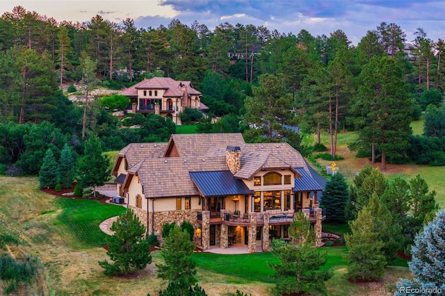 back house at dusk with a lawn and a wooden deck