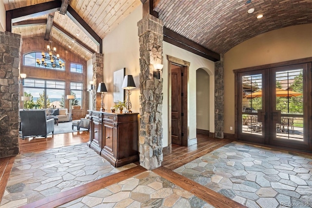 entrance foyer with a chandelier, beam ceiling, high vaulted ceiling, and french doors