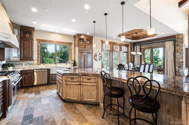 kitchen with pendant lighting, a kitchen island, dark stone countertops, and appliances with stainless steel finishes