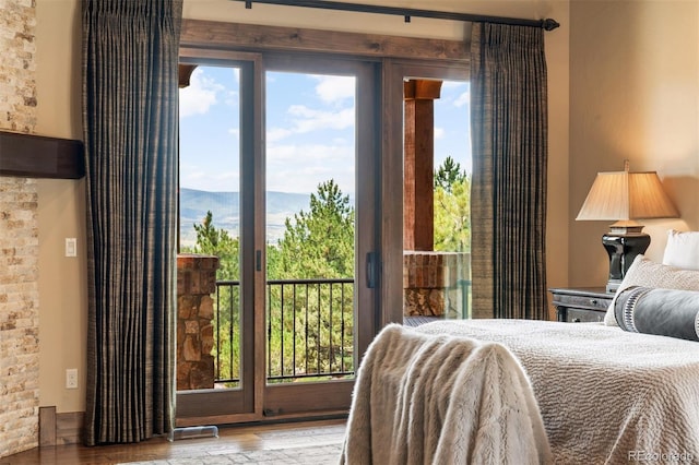 bedroom with hardwood / wood-style floors, a mountain view, access to outside, and multiple windows